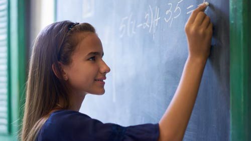 Girl writing math equations on a chalkboard