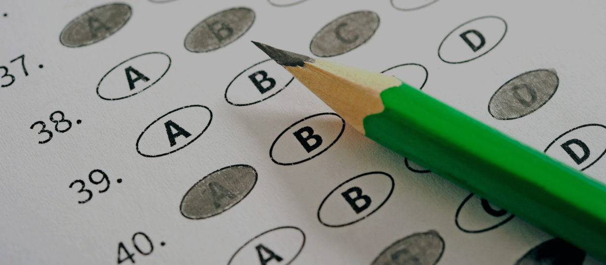 Close-up of a pencil resting atop a standardized test scoring sheet, commonly used for the act and sat, with answers a, b, c, or d filled in.