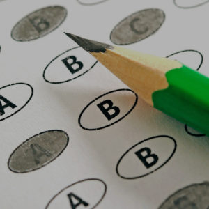 Close-up of a pencil resting atop a standardized test scoring sheet, commonly used for the ACT and SAT, with answers A, B, C, or D filled in.