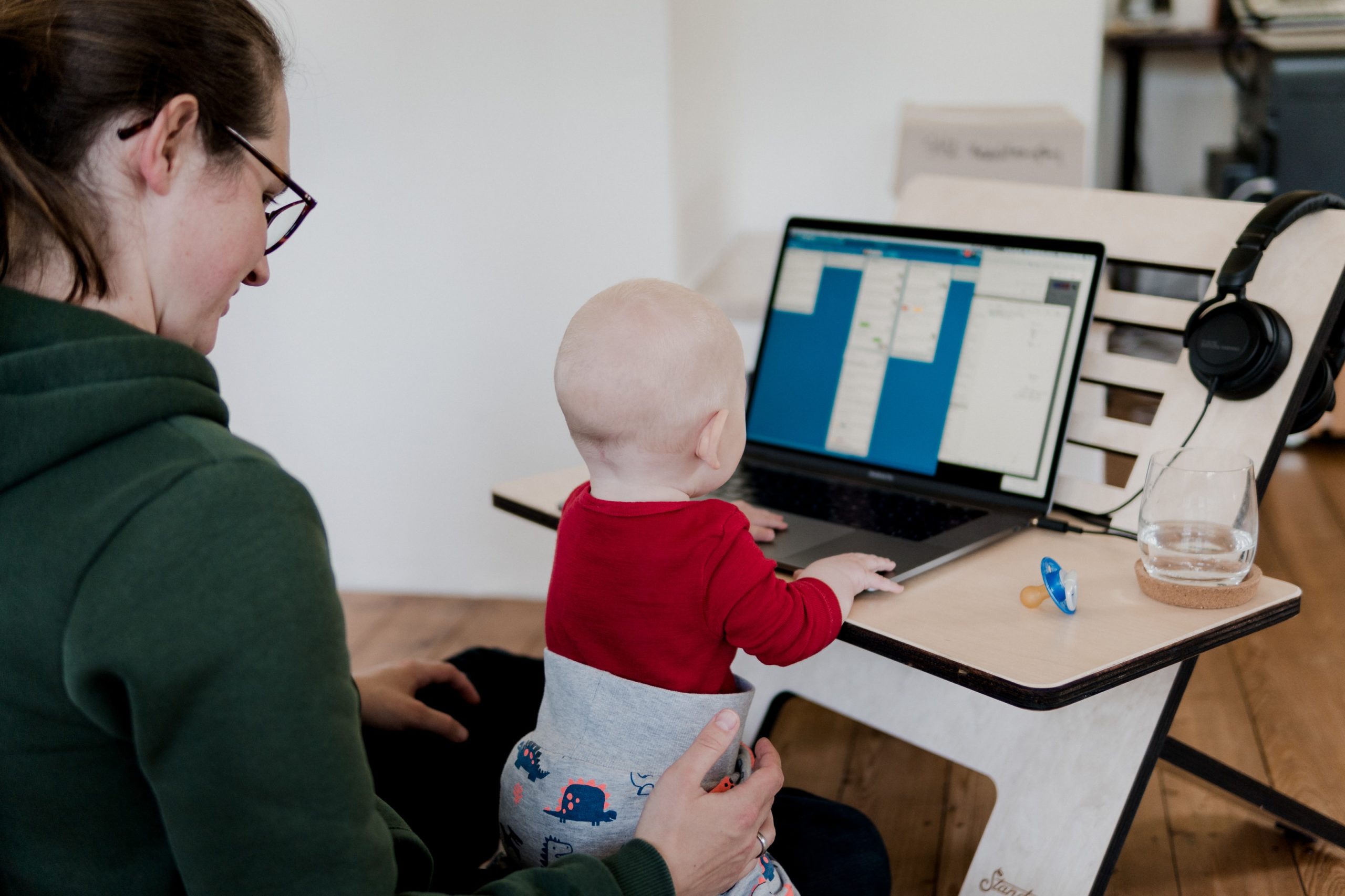 A mom multitasking by doing work with her baby A mom multitasking by doing work with her baby