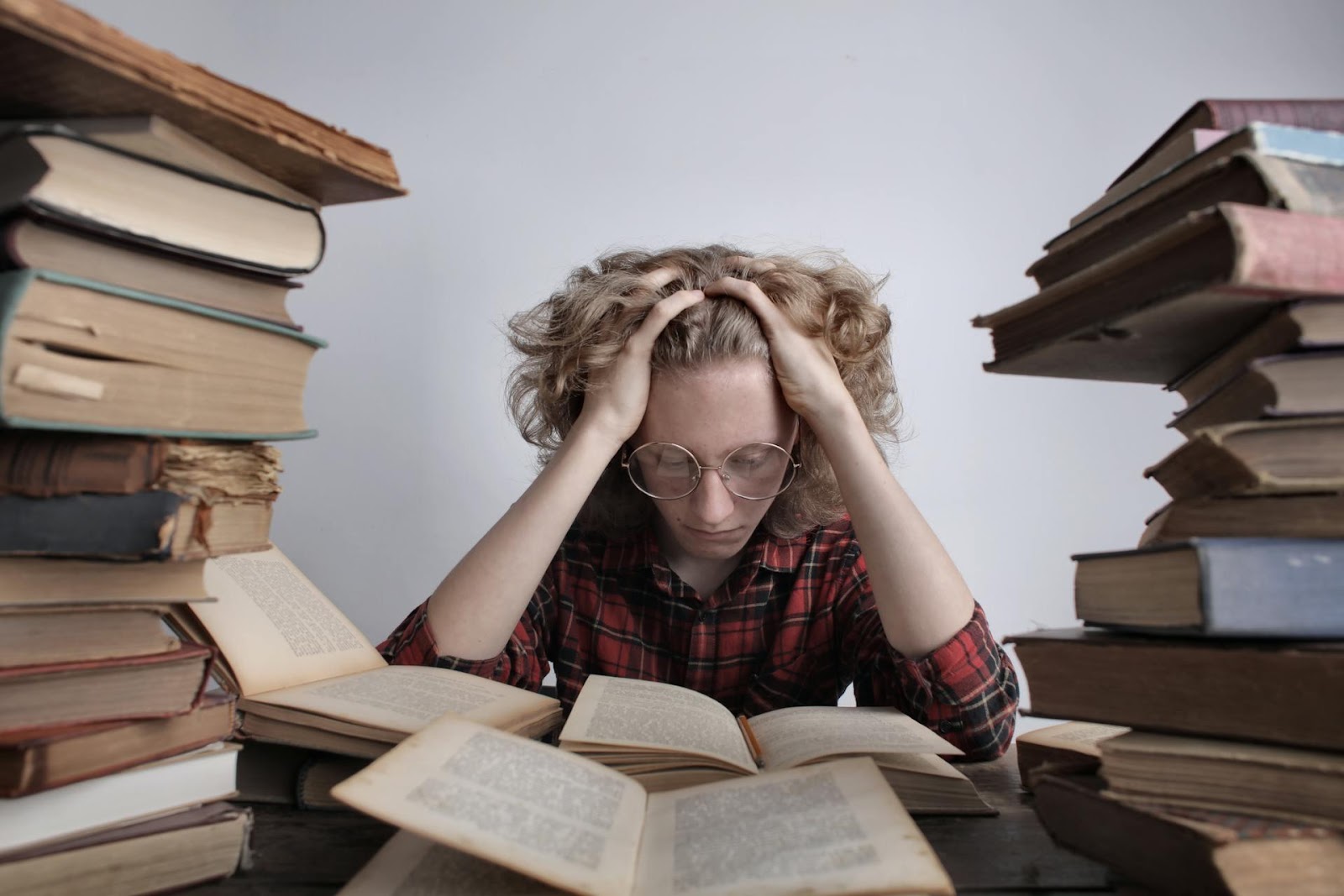 Student sitting among books with hands on his head