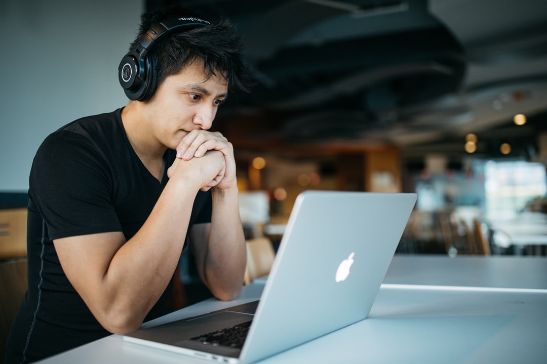 A young man wearing headphones works on his laptop studying AP math.