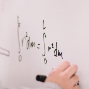 A closeup of a student working on math problems on a whiteboard.