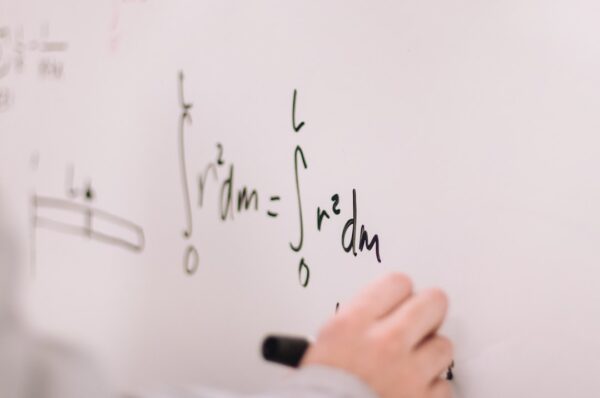 A closeup of a student working on math problems on a whiteboard.