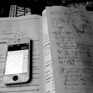 A phone calculator on top of a textbook and math tutoring notes.
