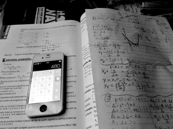 A phone calculator on top of a textbook and math tutoring notes.