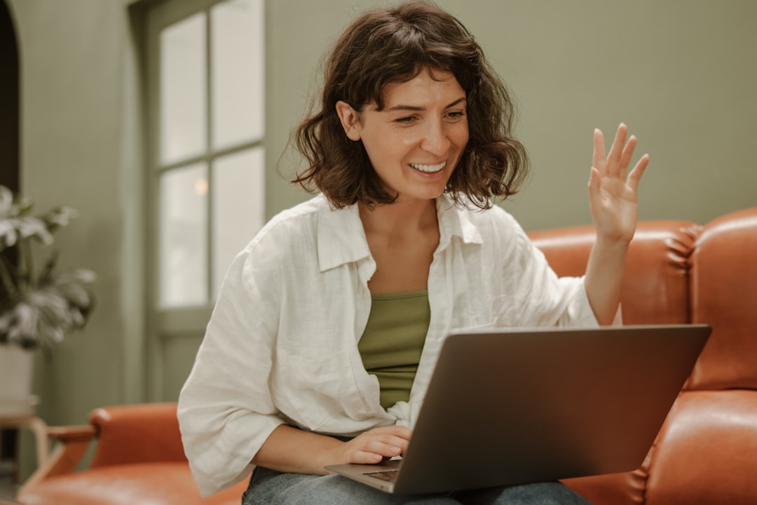 An online tutor giving her student a lesson on her laptop while sitting on the couch.
