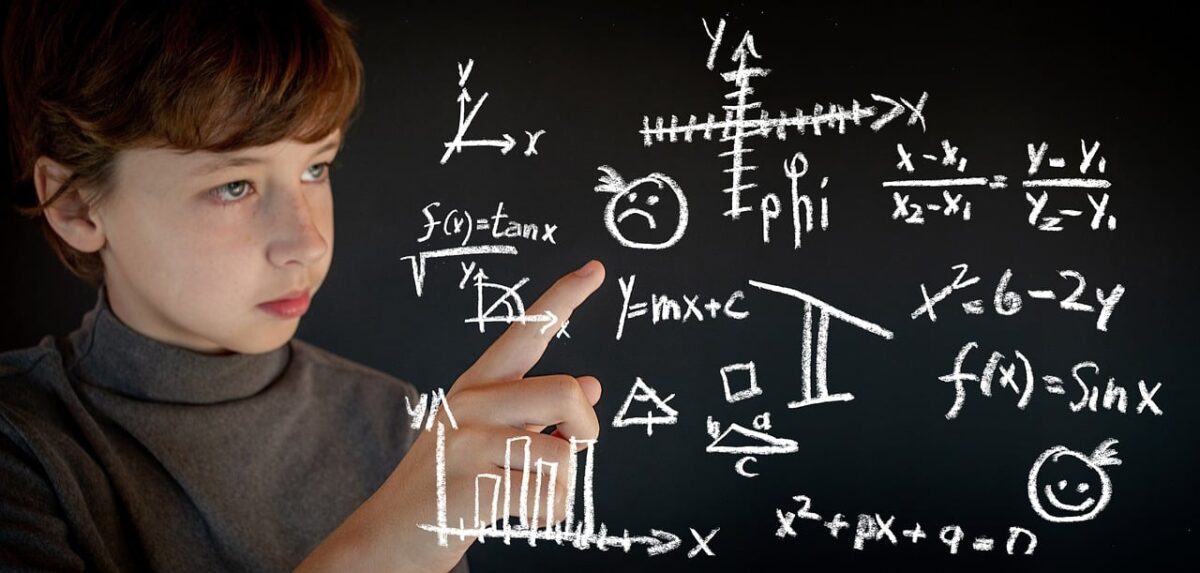 A young student points at math equations on a board.