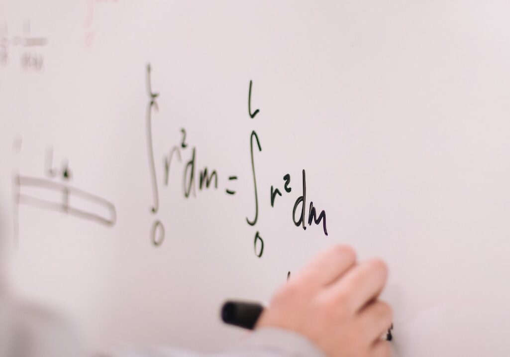 A closeup of a student working on math problems on a whiteboard.