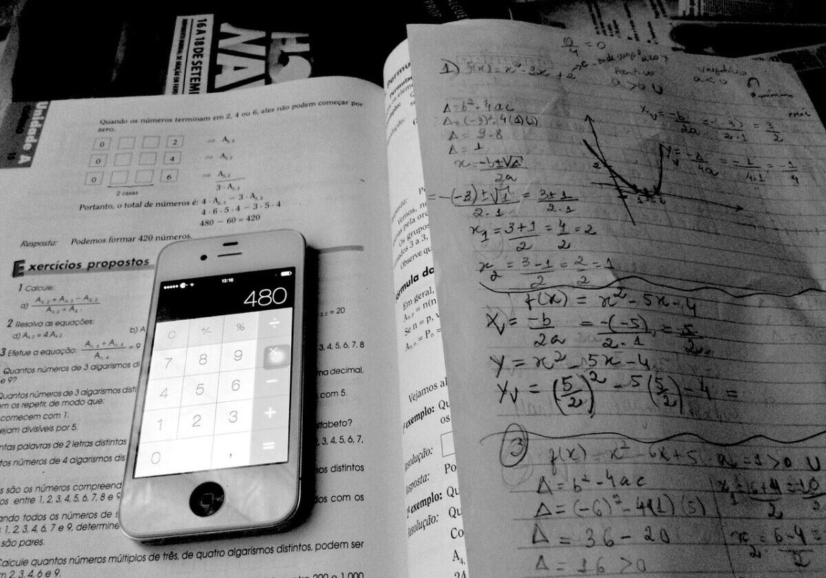 A phone calculator on top of a textbook and math tutoring notes.