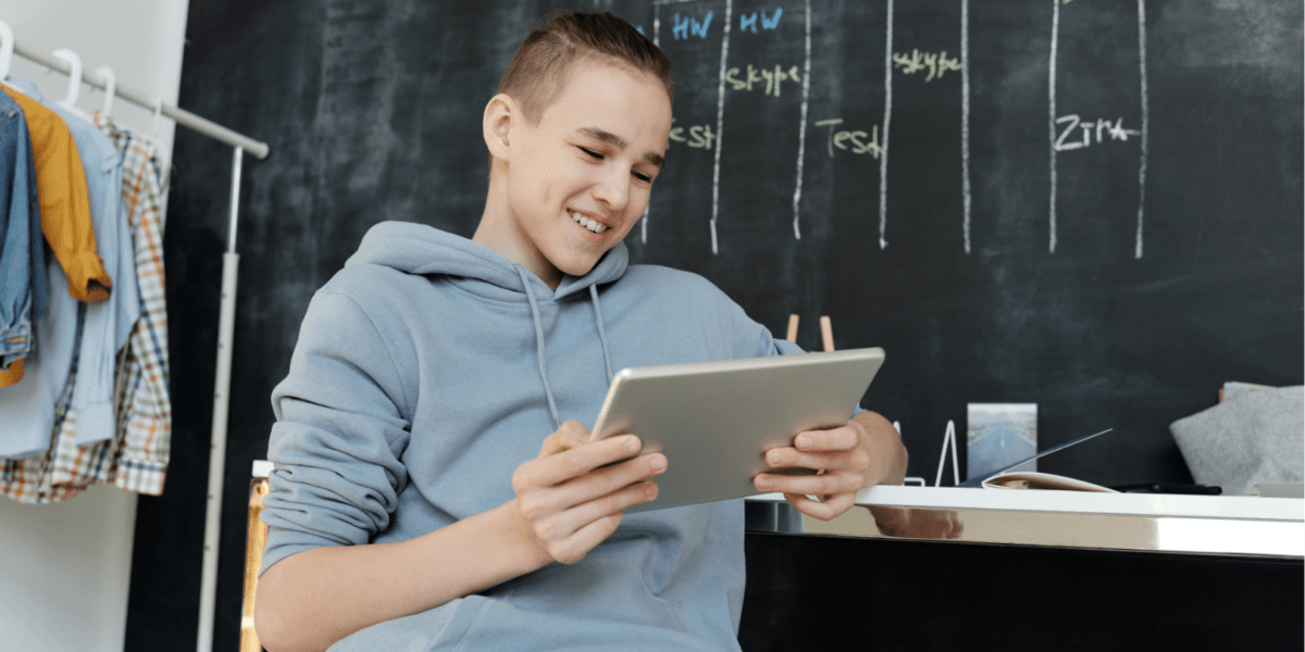 Boy sitting at desk looking at a tablet